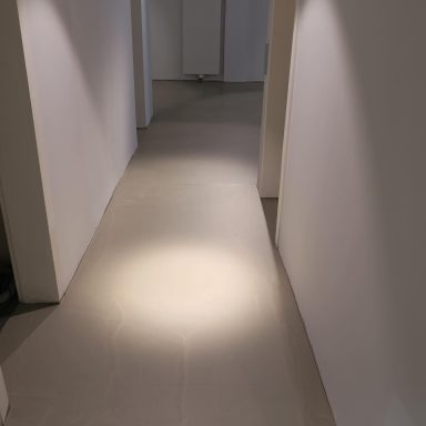 Mikrozement Boden Heller Flur mit LED-Beleuchtung und weißen Wänden, Bodenbelag in neutralen Tönen.