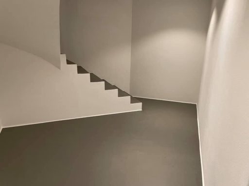 Mikrozement Boden Treppe Abgeschrägter Raum mit Treppe und sanften, neutralen Farben an Wänden und Boden.