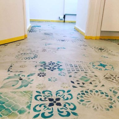 Mikrozement Boden Bunte, stenciled Muster auf einem grauen Fußboden in einem hellen Flur.